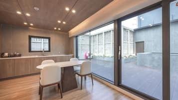 A modern kitchen with a dining area, large windows, and a view of the outside.