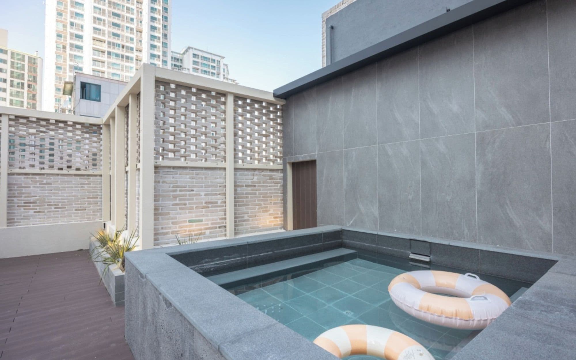 Una piscina en la azotea con dos sillas reclinables y una vista panorámica del paisaje urbano.