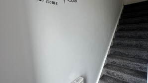 A staircase with a wall sign saying "Welcome to our home" and a white radiator.