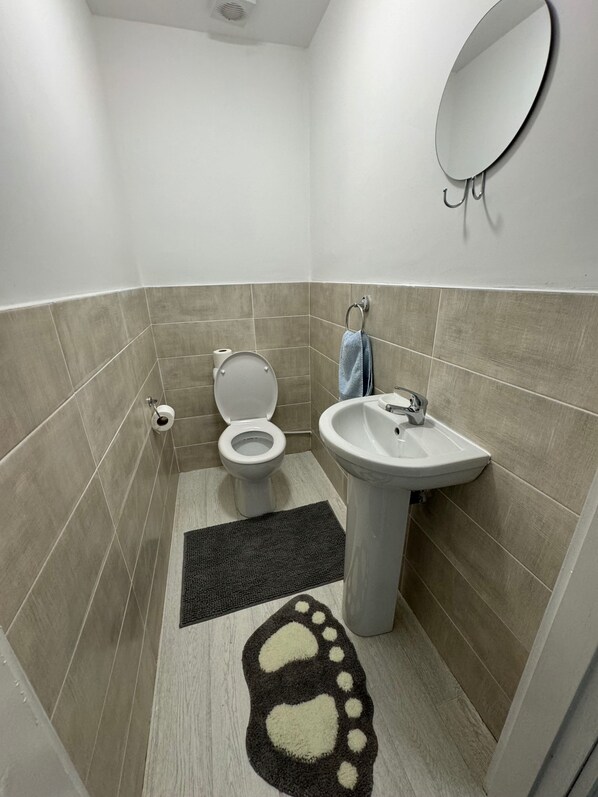 Un baño con inodoro, lavamanos, espejo y un tapete estampado en el suelo.