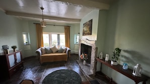 Ein gemütliches Wohnzimmer mit Kamin aus Stein, einer Couch mit Kissen, einem runden Teppich und einem Holztisch mit Dekoration.