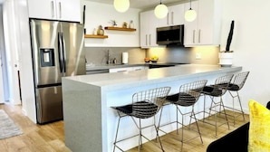 A modern kitchen with a central island, stainless steel appliances, and bar-style seating. - Location, Location, Location - Shadow Mountain Resort South Palm Desert  (Palm Desert)