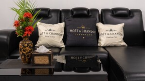 A black leather sofa with three pillows, one of which has the text "MOËT & CHANDON CHAMPAGNE". A vase with red flowers and a decorative box are on the table in front of the sofa. - Villa - Sleeps 8 - Terrace - Beach Close (Ko Lanta)