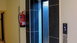 An elevator with a fire extinguisher mounted on the wall beside it. - Elclassico Studio Jkia Airport View (Nairobi)