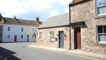 A street view with stone buildings, a red door, and a clear sky.