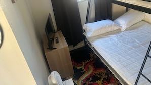A bunk bed with white bedding, a desk with a computer and remote control, a fan, and a decorative dragon rug. - Great Yarmouth - Chalet - Sleeps 5 - Parking (Great Yarmouth)