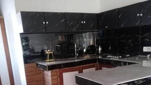 Een moderne keuken met zwarte marmeren aanrechtbladen, houten keukenkastjes en een wit keukenblok.