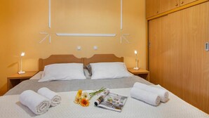 Une chambre d’hôtel avec un lit, deux lampes de chevet, une armoire en bois et un mur orné de luminaires aux formes géométriques.