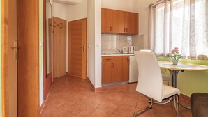 Une cuisine de taille réduite, avec des meubles en bois, une chaise blanche et une petite table à manger.