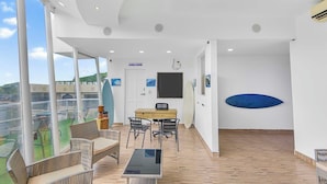 A spacious balcony with a dining area, a surfboard, and a view of the sea. - Surfo House (Tamarindo)