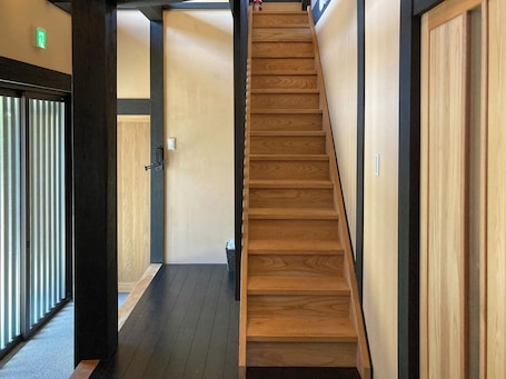 A wooden staircase in a hallway with a door on the left and a wall on the right.