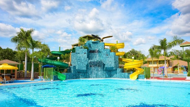 Una piscina con tobogán y formación rocosa.