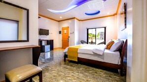Habitación de hotel con cama, escritorio, silla, televisor y ventana con vista al exterior.