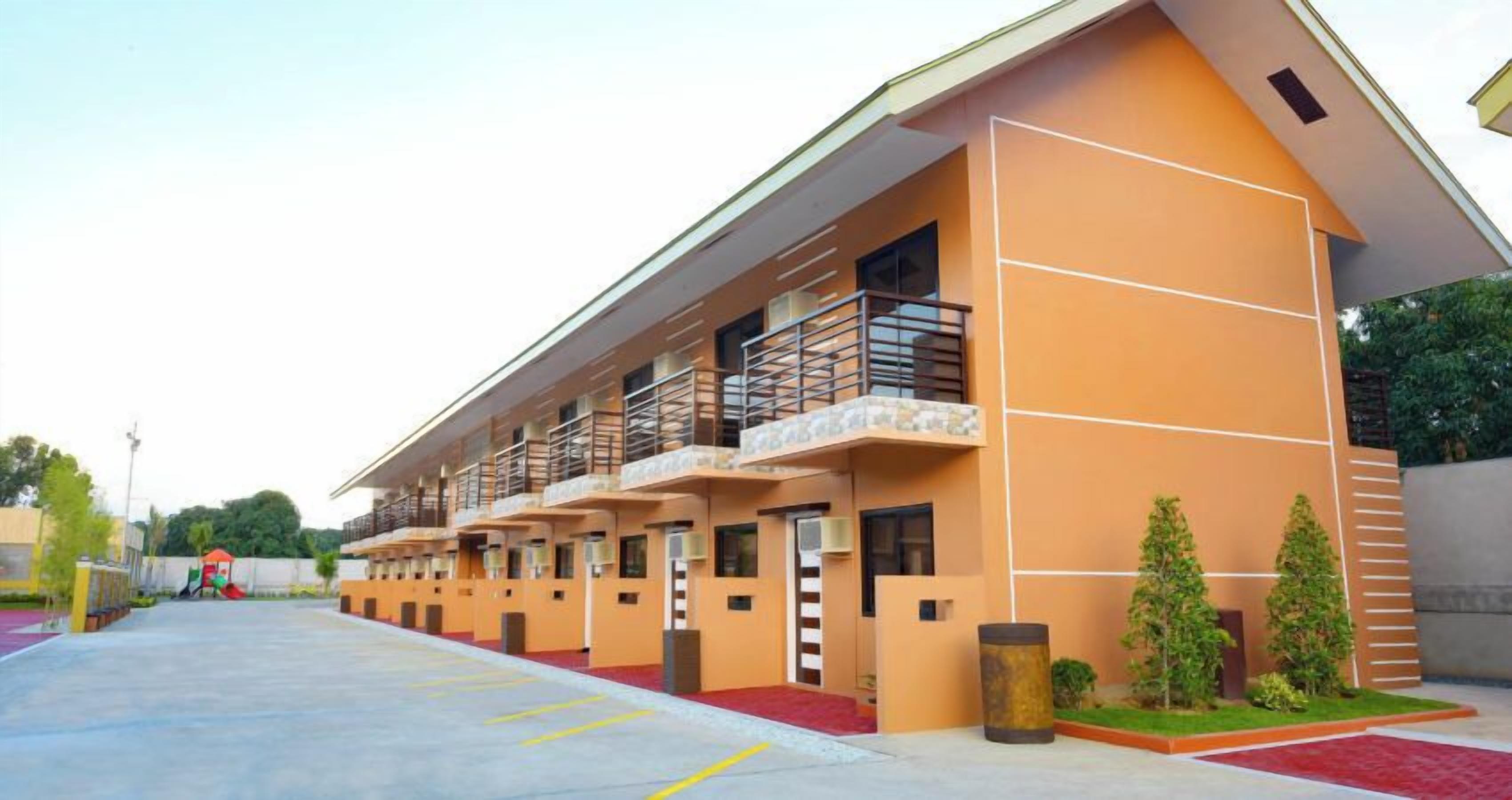 A multi-story hotel with a modern design, featuring balconies and a red carpet entrance.