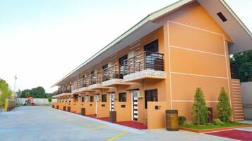 A multi-story hotel with a modern design, featuring balconies and a red carpet entrance.