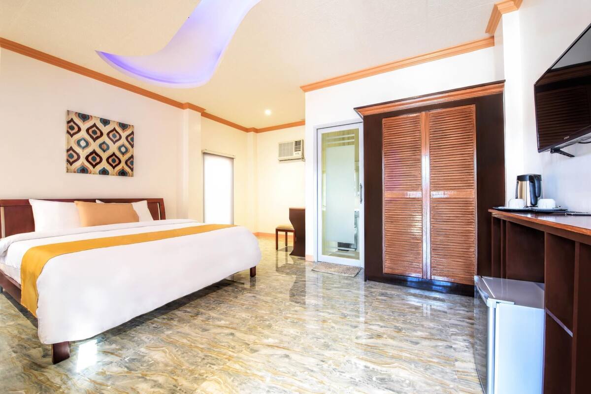 A hotel room with a bed, a desk, a coffee maker, and a sliding door.