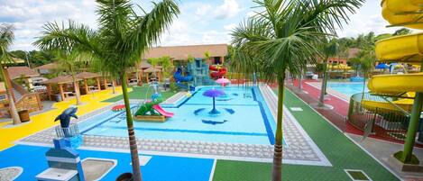 Un parque acuático con toboganes, piscina y palmeras.