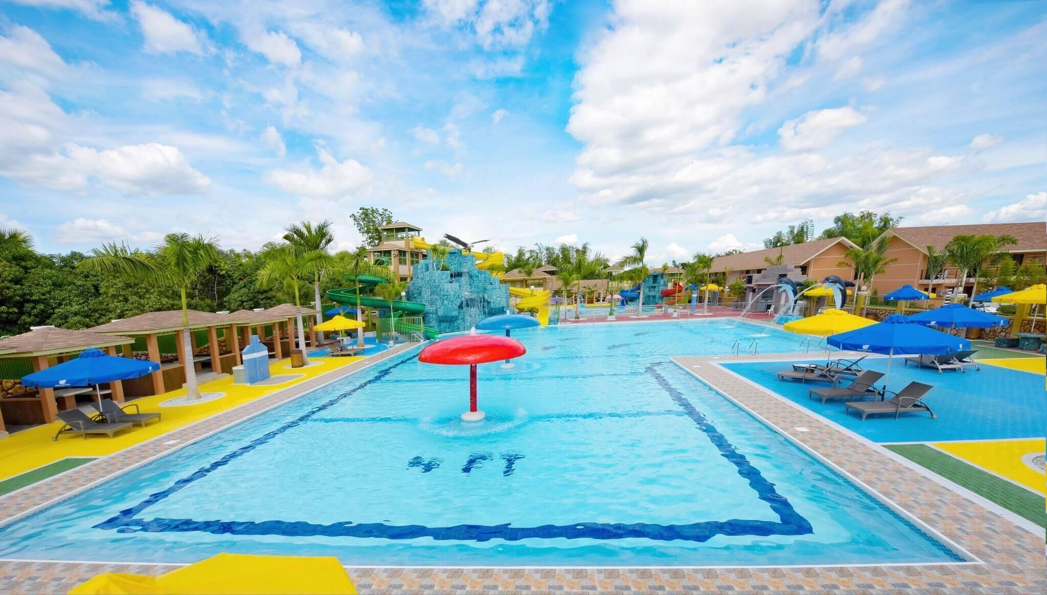 A large swimming pool with a water slide, surrounded by lounge chairs and umbrellas.