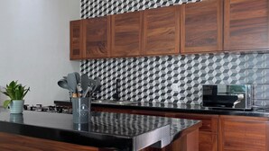 Une cuisine avec des meubles en bois, un plan de travail noir, un four à micro-ondes et un crédence décorée.