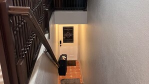Eine Treppe mit Handlauf, eine Tür mit dekorativem Glasfenster und ein kleiner Teppich am Fuß.