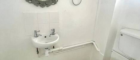 A bathroom with a white sink, mirror, and toilet.