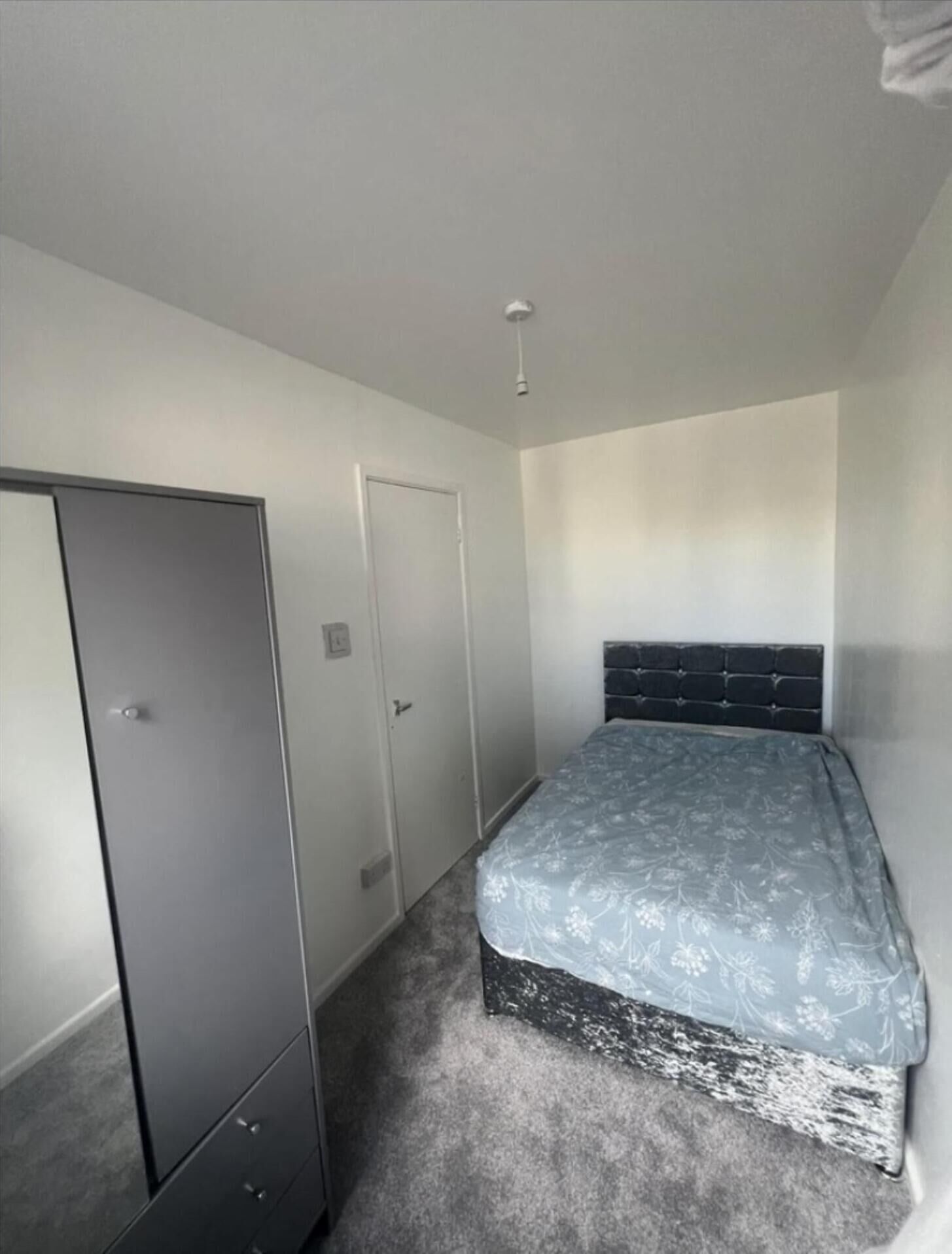 A bedroom with a bed, a wardrobe, and a door.
