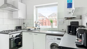 Une cuisine moderne avec des meubles blancs, une cuisinière encastrée, un lave-vaisselle et une machine à laver.