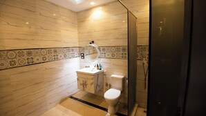 A modern bathroom with a marble floor, a toilet, a sink with a mirror, and a shower area. - King Tut Hotel Museum & Pyramids View (Giza)