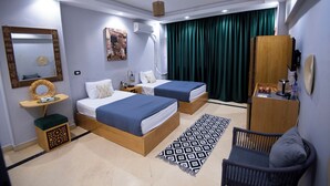 A modern hotel room with two beds, a small desk, a chair, a large mirror, and a green curtain. - King Tut Hotel Museum & Pyramids View (Giza)