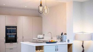 A modern kitchen with white cabinetry, a built-in oven, a sink, and a fruit bowl on the counter. - Executive 4-bed house in vibrant village center

 (WALTHAM)