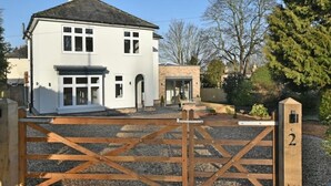 A white two-story house with a front porch and a wooden gate. - Executive 4-bed house in vibrant village center

 (WALTHAM)