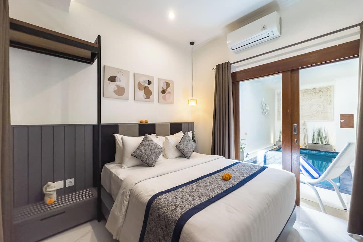 A modern hotel room with a bed, bedside table, and artwork on the wall.