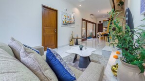 A modern living room with a sofa, a coffee table, and a potted plant. - De Amelia Seminyak Villa by Nagisa Bali (Denpasar)