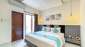 A modern hotel room with a large bed, a ceiling fan, a wall-mounted air conditioner, and a view of the outdoors through a sliding door. - De Amelia Seminyak Villa by Nagisa Bali (Denpasar)