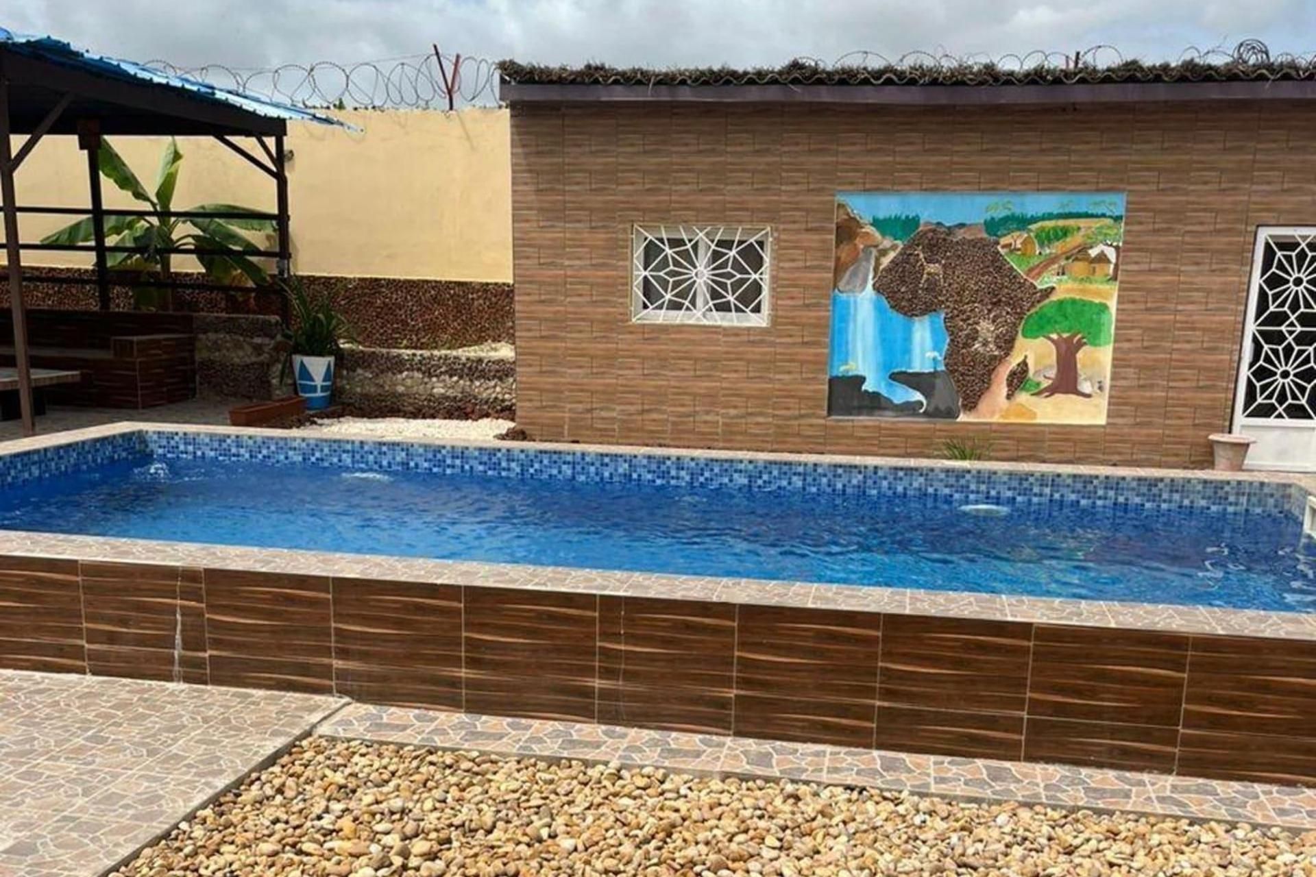 Une piscine avec un bord carrelé, une fresque représentant une cascade et un mur de briques agrémenté de fenêtres.