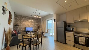 A modern kitchen with a dining area, a flat-screen TV, and a stone accent wall.