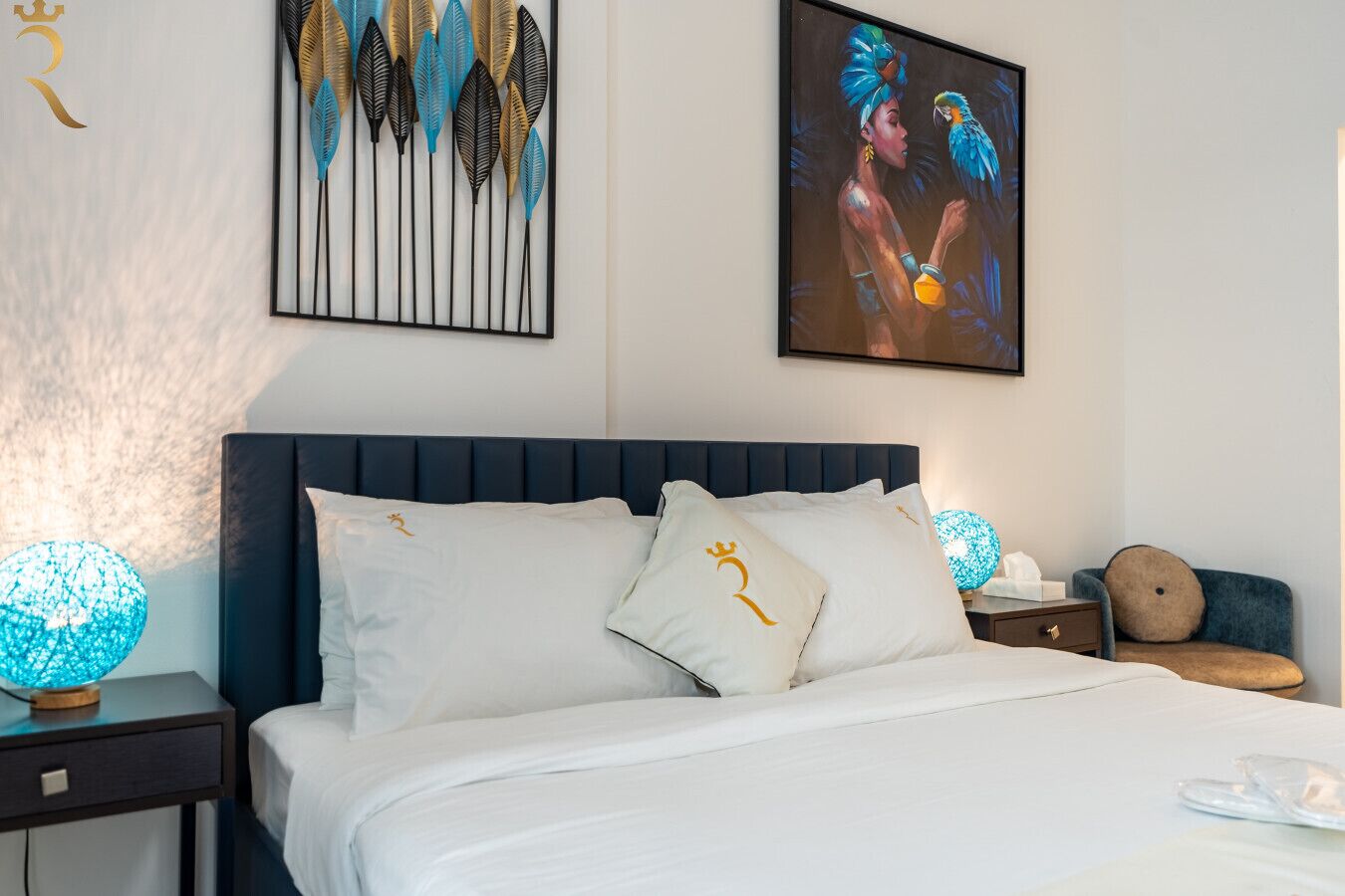 Un lit bien fait, avec une literie blanche, une tête de lit sombre et des coussins décoratifs ornés de motifs dorés.