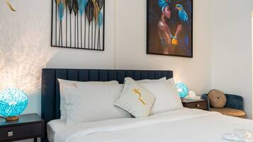 Un lit bien fait, avec une literie blanche, une tête de lit sombre et des coussins décoratifs ornés de motifs dorés.