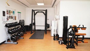 Une salle de sport équipée d’un support à squats, d’haltères et d’appareils de musculation.