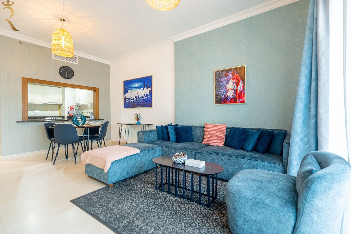 A modern living room with a blue sofa, a coffee table, and a dining area with chairs and a table.
