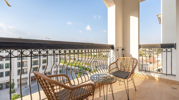 Un balcon donnant sur le paysage urbain, deux fauteuils en osier et une petite table ronde.