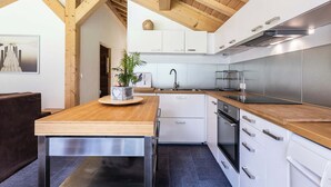 Una cocina moderna con vigas de madera, armarios blancos y electrodomésticos de acero inoxidable.