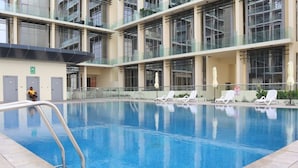 En pool med solstolar och ett glasräcke.