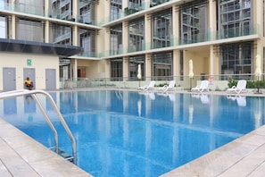 Ein Schwimmbecken mit Liegestühlen und einer Glasbrüstung.