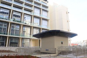 Ein modernes Gebäude mit mehreren Etagen, großen Fenstern und einem überdachten Eingangsbereich.