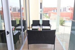 A balcony with wicker furniture and a glass door.