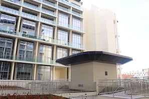 A modern building with multiple floors, large windows, and a covered entrance area.