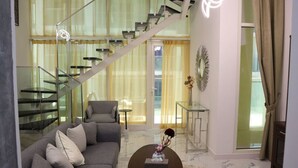 Una sala de estar moderna con un sofá gris, una mesa de centro y una escalera que sube a un nivel superior.