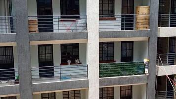 A multi-story residential building with balconies, some with furniture and items.