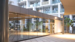 Un edificio moderno con fachada de vidrio, zona de estar exterior y un paseo techado.